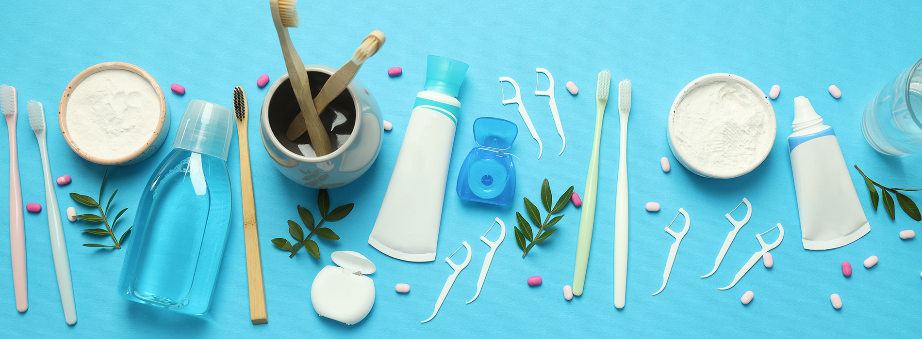 The image shows a collection of items related to personal hygiene and care, including toothbrushes, toothpaste, facial skincare products, and other beauty supplies, arranged on a blue background with some items in front of a white backdrop.
