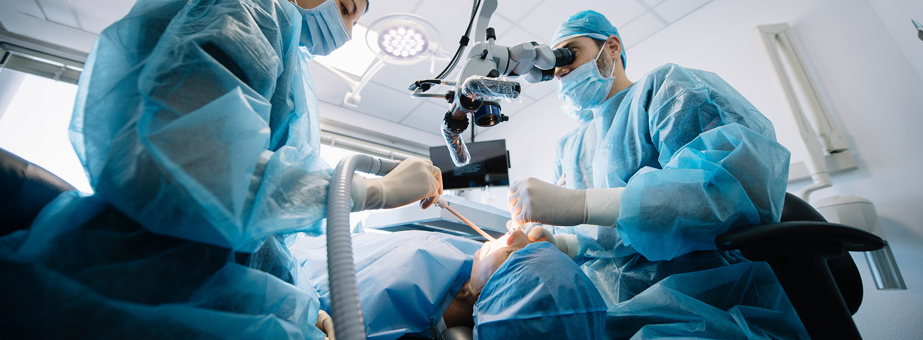 A medical professional performing a procedure in an operating room while wearing protective gear.