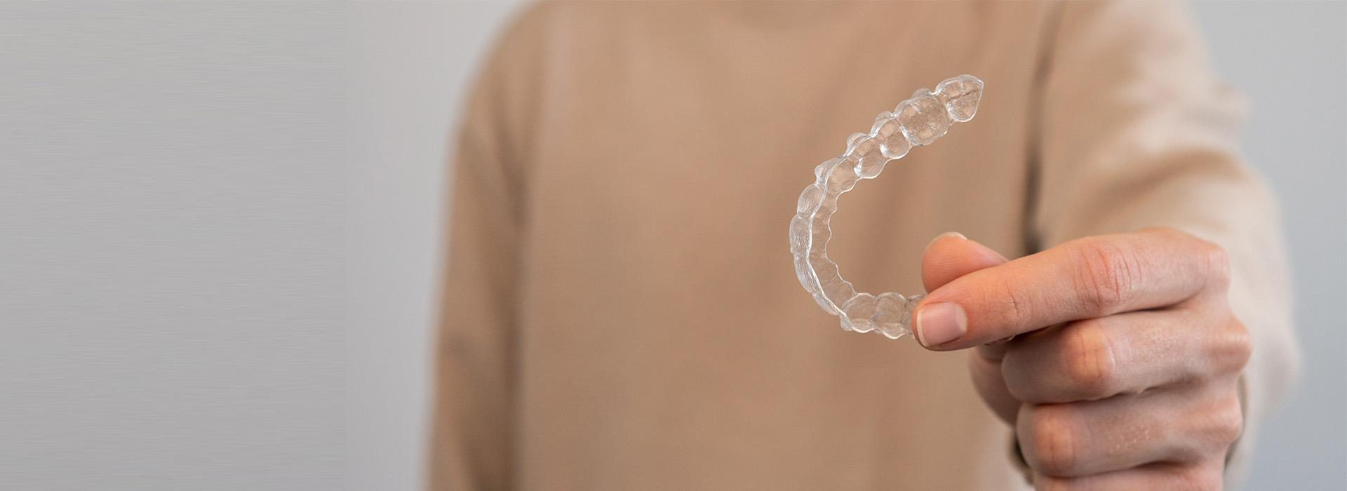 A person s hand holding an object that resembles a soap bubble against a neutral background.
