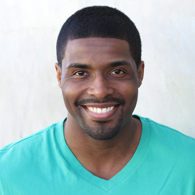 The image depicts two older adults, a man and a woman, smiling and embracing each other closely. They are seated outdoors during daylight, with a clear sky above them.