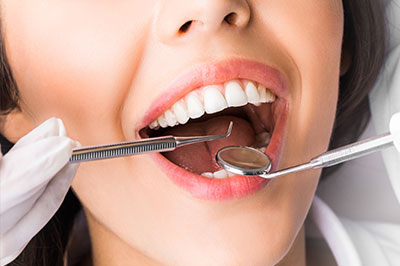The image shows a person with a wide smile, holding a toothbrush near their mouth, which appears to be a part of a dental care setting, possibly for demonstration or promotion purposes.