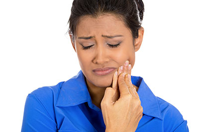 The image shows a woman with her mouth open, holding her finger near her teeth, possibly indicating pain or discomfort.