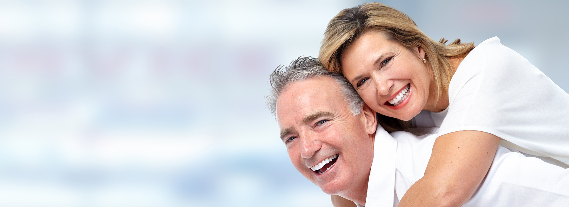 The image features a man and woman smiling at the camera  they are embracing each other with their arms around one another, suggesting a close relationship such as marriage or a long-term partnership.