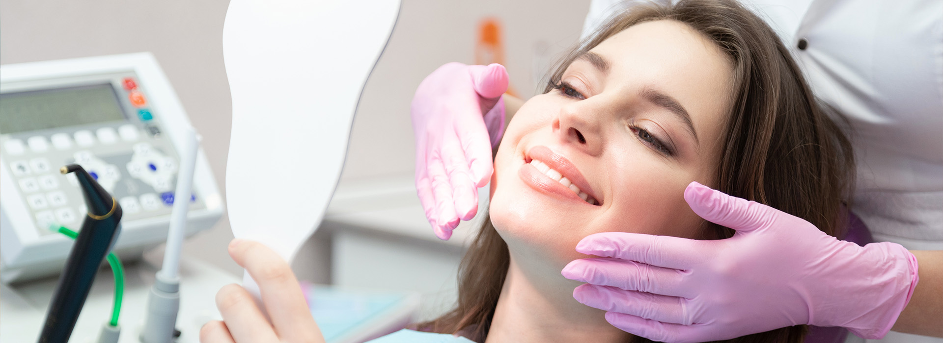 A woman receiving dental care with a dentist using an instrument on her teeth.