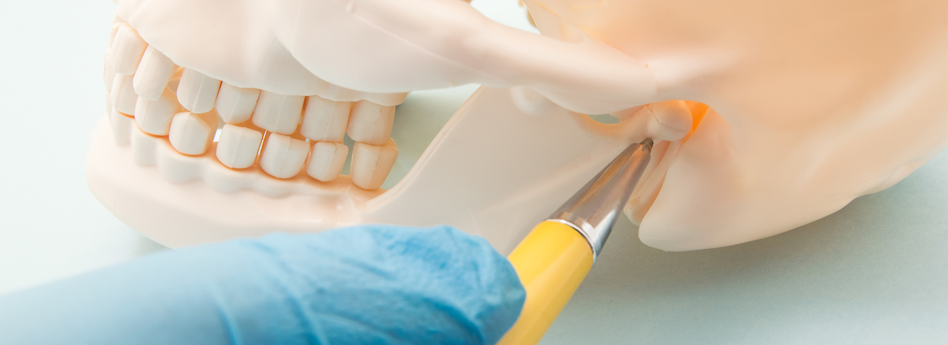 A close-up view of a dental procedure in progress, with a dentist s hand holding a drill near a tooth model inside a mannequin head.