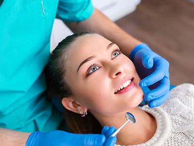 A dental professional performing a procedure on a patient s teeth using a drill.